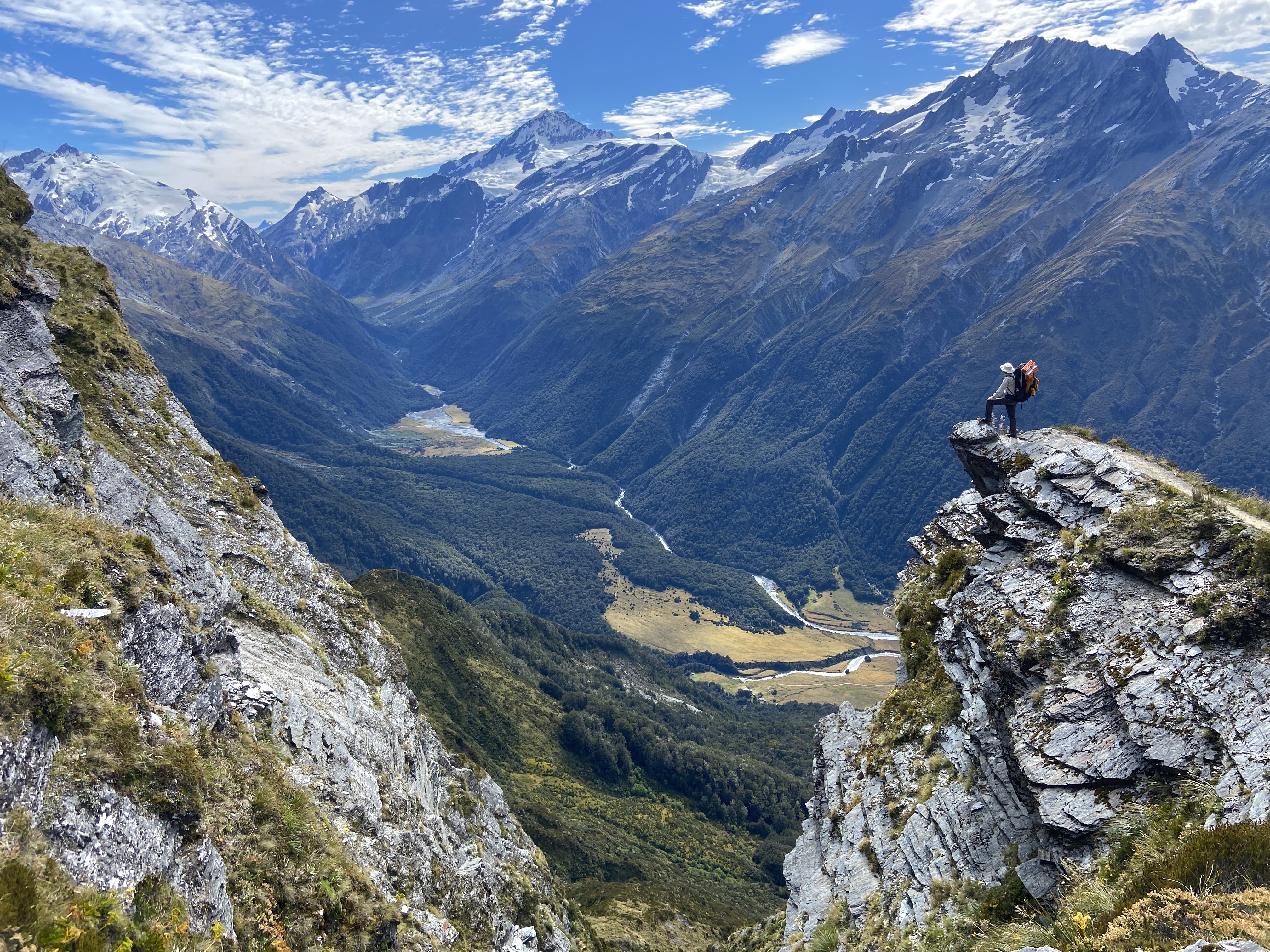 A tramper on a rocky outcrop above the Mātakitaki valley