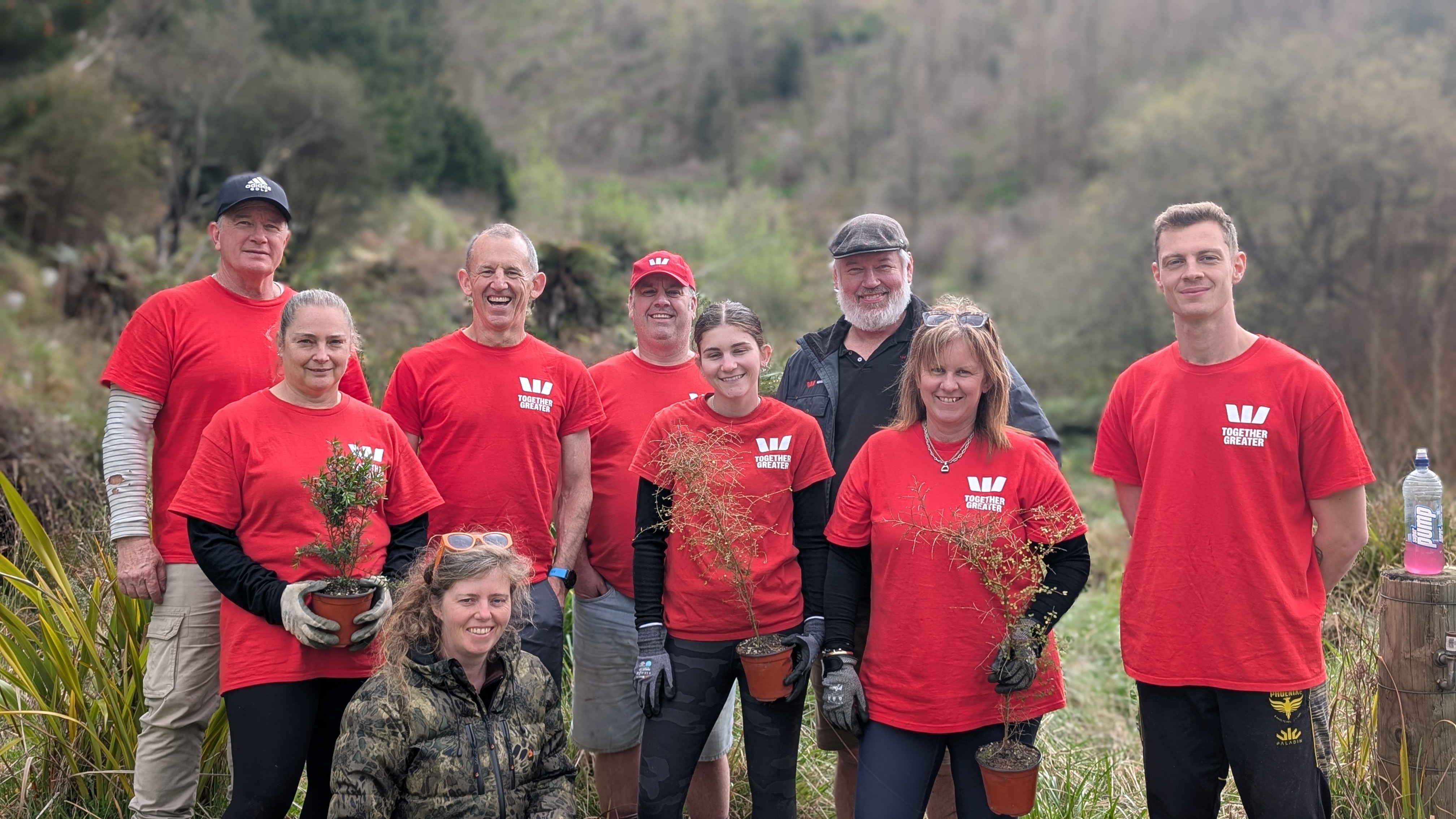 A corporate volunteer team holding native seedlings at the 800 block